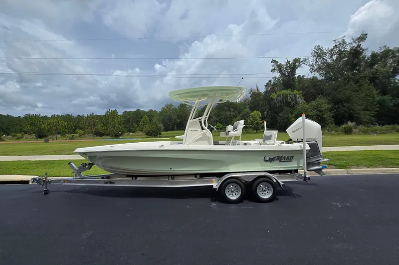 The Image of 2026 Mako 24 APEX boat on trailer, parked outdoors under cloudy sky. - 0