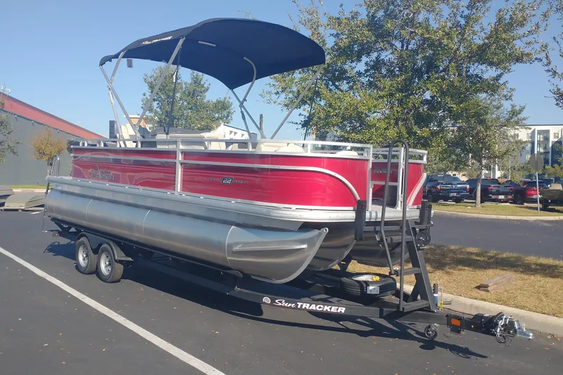 The Image of 2026 Sun Tracker Fishin' Barge 22 XP3 pontoon boat on trailer in parking lot. - 0