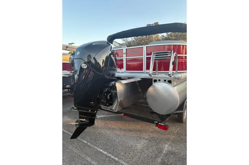 Slide: The Image of 2026 Sun Tracker Party Barge 22 XP3 with powerful outboard motor, parked on trailer. - 2