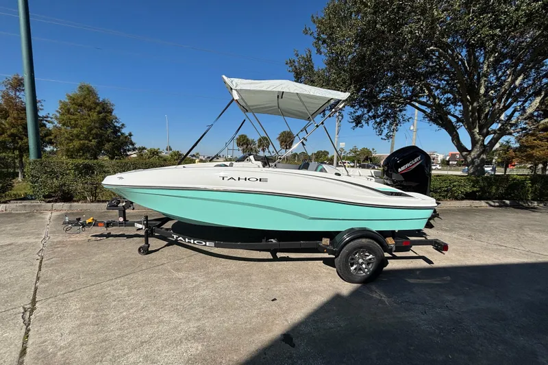 The Image of 2026 Tahoe T16 boat with canopy on trailer, parked outdoors under clear blue sky. - 0