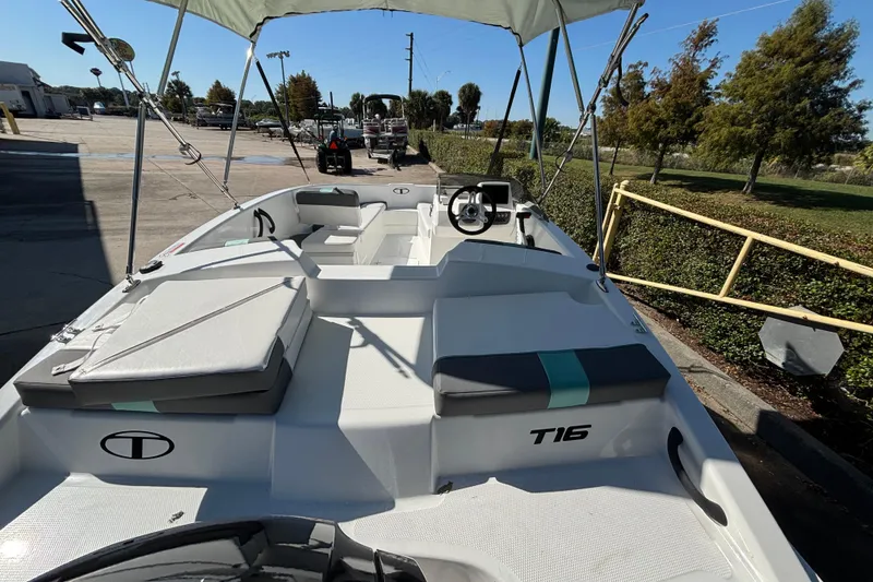 Slide: The Image of 2026 Tahoe T16 boat with canopy, parked outdoors on a sunny day. - 2
