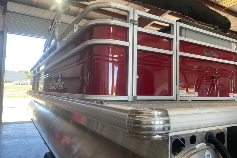 Slide: The Image of 2026 Sun Tracker SportFish 22 XP3 pontoon boat in a garage, featuring a sleek red exterior. - 3