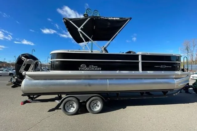Slide: The Image of 2026 Sun Tracker Party Barge 22 DLX pontoon boat on trailer, under clear blue sky. - 90
