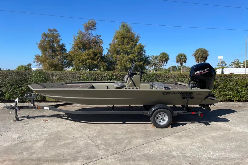 The Image of 2026 Tracker Grizzly 1860 CC boat on trailer, parked outdoors under clear blue sky. - 0