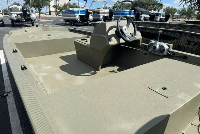 Slide: The Image of 2026 Tracker Grizzly 1648 SC boat, olive green, steering console, parked outdoors. - 8