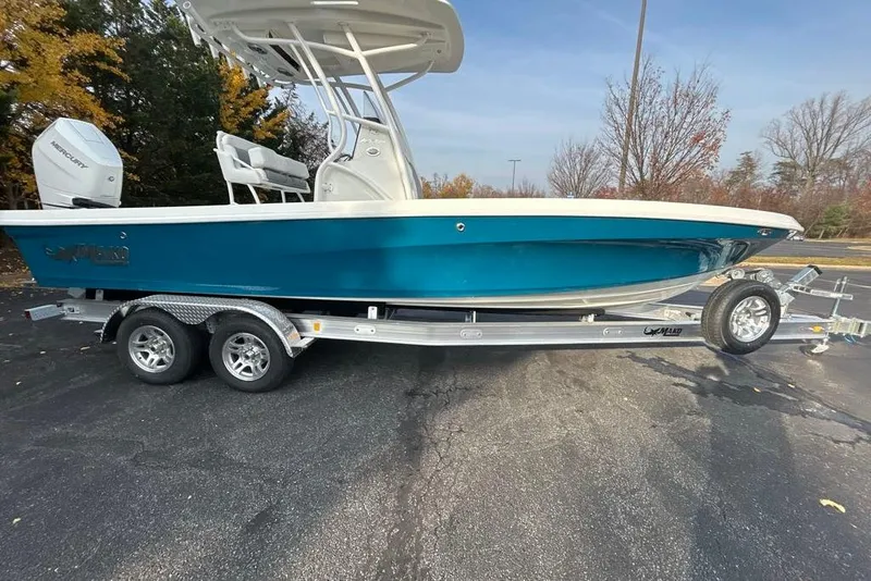 The Image of 2026 Mako 24 APEX boat on trailer, blue hull, parked outdoors. - 0