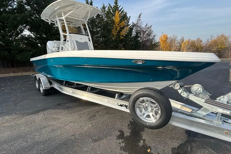 Slide: The Image of 2026 Mako 24 APEX boat on trailer, parked outdoors with autumn trees in background. - 1