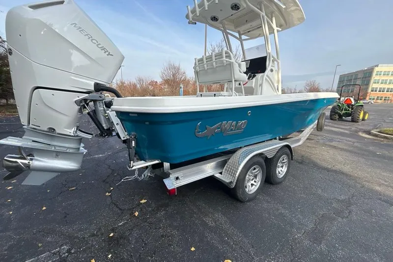 Slide: The Image of 2026 Mako 24 APEX boat with Mercury engine on trailer in parking lot. - 2