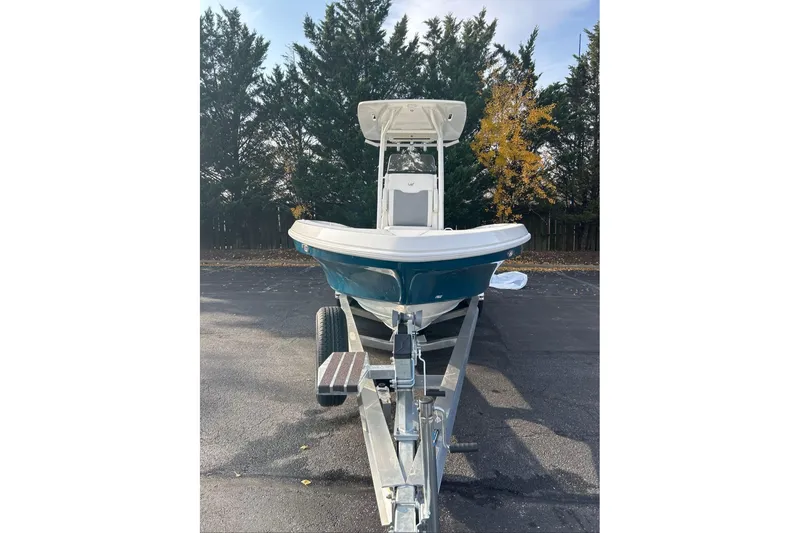 Slide: The Image of 2026 Mako 24 APEX boat on trailer, parked outdoors with trees in background. - 3