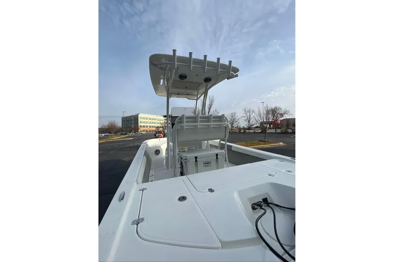 Slide: The Image of 2026 Mako 24 APEX boat with T-top, parked outdoors under a cloudy sky. - 9