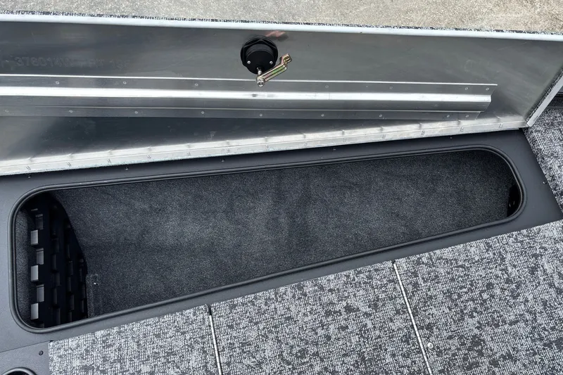 Slide: The Image of Storage compartment of 2026 Tracker Pro Team 195 boat, featuring carpeted interior and metal latch. - 18