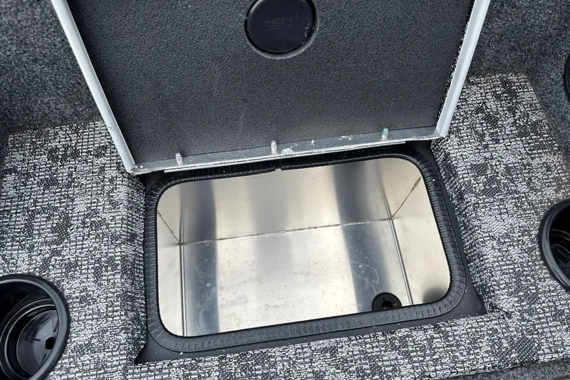 Slide: The Image of Open storage compartment in 2026 Tracker Pro Team 195 boat, featuring textured flooring and cup holders. - 22