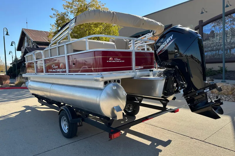 Slide: The Image of 2024 Sun Tracker Party Barge 18 DLX pontoon boat on trailer, featuring Mercury outboard motor. - 2