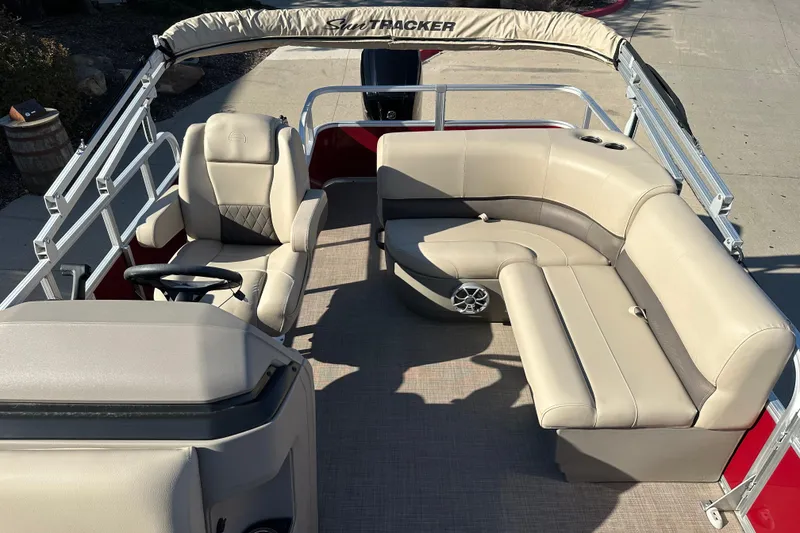 Slide: The Image of 2024 Sun Tracker Party Barge 18 DLX interior with beige seating and steering console. - 6