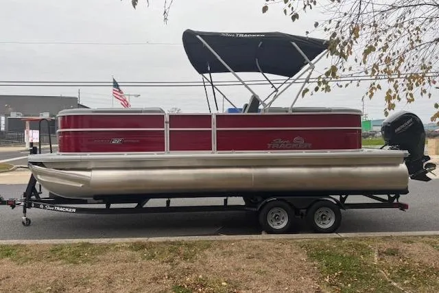 Slide: The Image of 2026 Sun Tracker Party Barge 22 DLX pontoon boat on trailer, parked outdoors. - 1