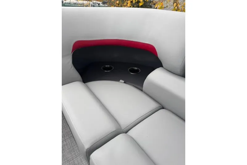 Slide: The Image of 2026 Sun Tracker Party Barge 22 DLX interior seating with cup holders and red accent. - 10