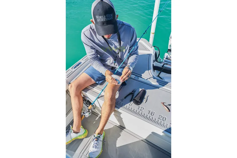 Slide: The Image of Man fishing on a 2026 Mako 24 APEX boat, preparing tackle. - 83