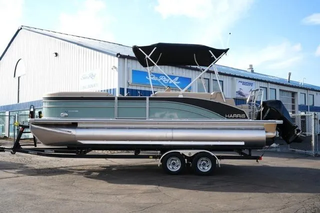 The Image of 2026 Harris Cruiser 230 pontoon boat on trailer, parked outside a marine dealership. - 3