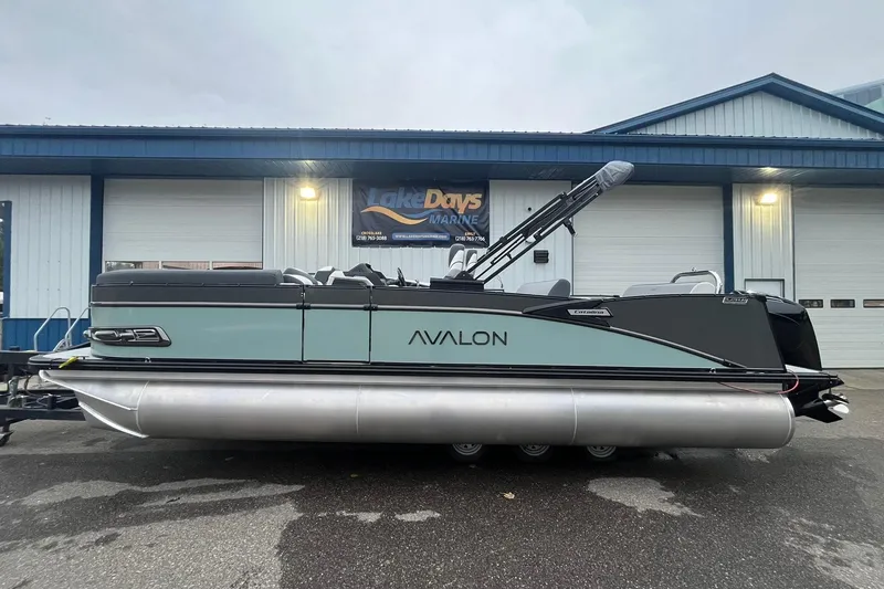 The Image of 2026 Avalon Catalina Versatile Rear Lounger pontoon boat parked outside a marine shop. - 1