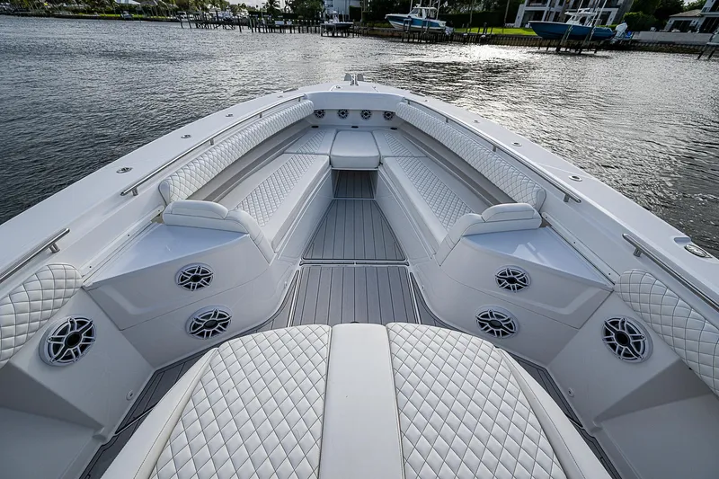 Slide: The Image of 2023 HCB 53 Sueños boat interior with luxurious seating and speakers on a calm waterfront. - 4