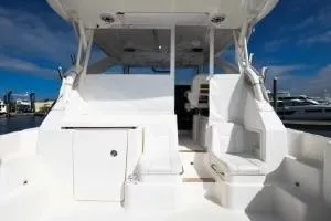 Slide: The Image of 2021 Pursuit OS 355 Offshore boat interior with seating and storage, docked under blue sky. - 10