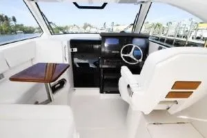 Slide: The Image of 2021 Pursuit OS 355 Offshore boat interior with steering wheel and seating area. - 13