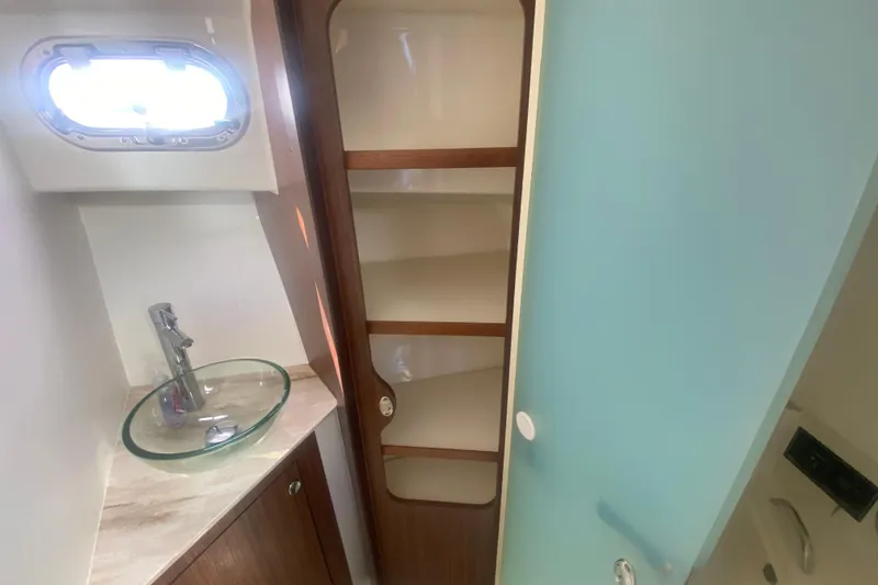 Slide: The Image of 2021 Pursuit OS 355 Offshore bathroom with glass sink and wooden shelving. - 31