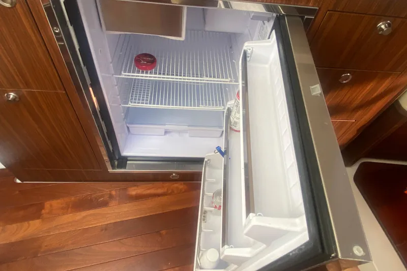 Slide: The Image of Open refrigerator inside 2021 Pursuit OS 355 Offshore boat, featuring wooden cabinetry. - 37
