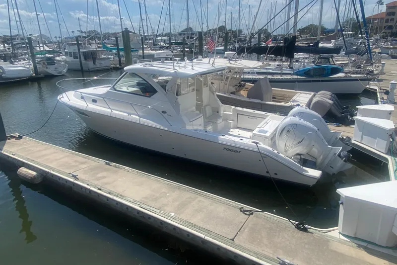 Slide: The Image of 2021 Pursuit OS 355 Offshore boat docked at a marina with other vessels. - 50