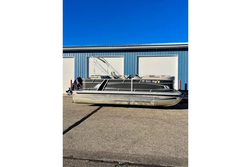 Slide: The Image of 2021 SMOKERCRAFT EX20C pontoon boat parked outside a blue warehouse. - 1