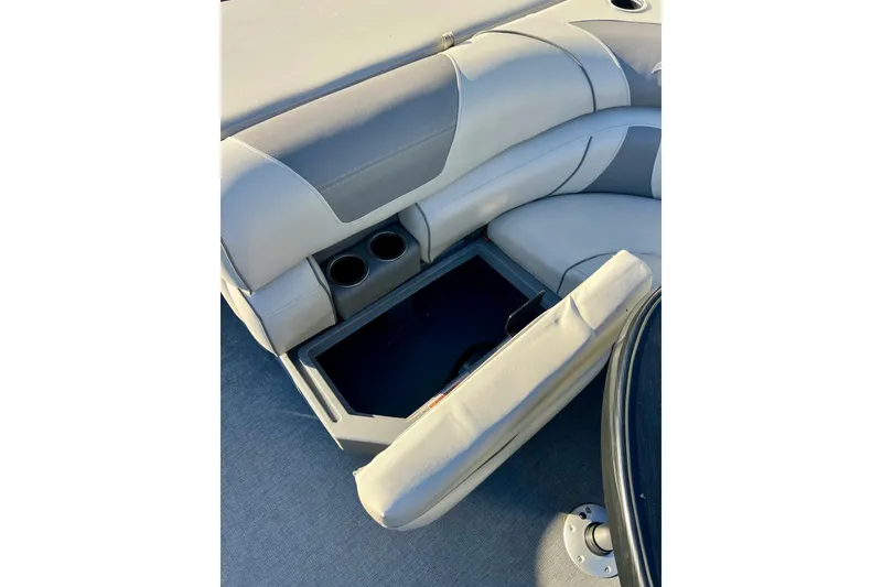 Slide: The Image of 2021 SMOKERCRAFT EX20C boat with gray seating and cup holders, parked near a blue building. - 46