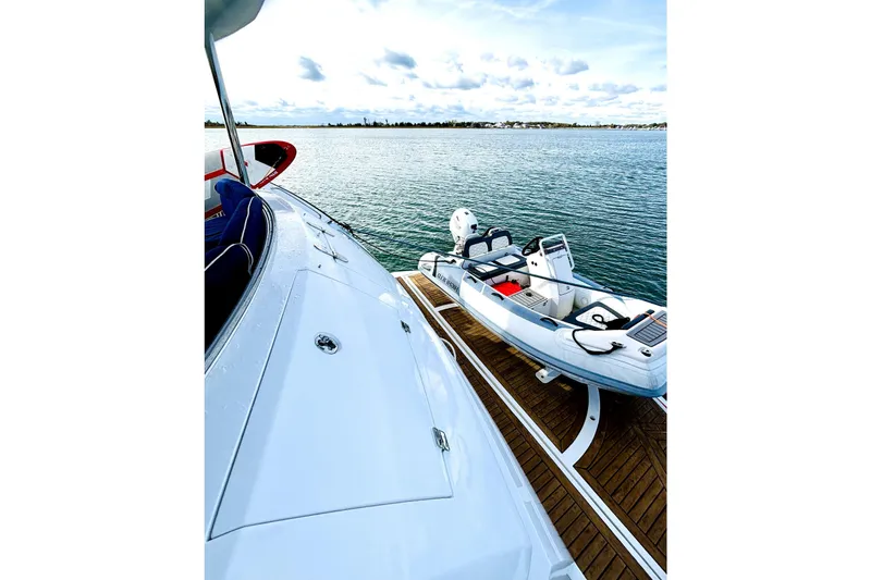 Slide: The Image of Sunseeker 75 Sport Yacht 2005 on water with small boat, clear sky, and wooden deck. - 43