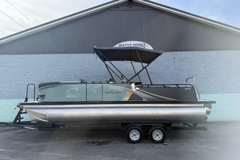 The Image of 2026 Avalon 2385 LSZ Entertainer pontoon boat on trailer, parked by a building. - 1