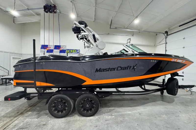 Slide: The Image of 2017 MasterCraft X23 boat with black and orange design on a trailer in a garage. - 6