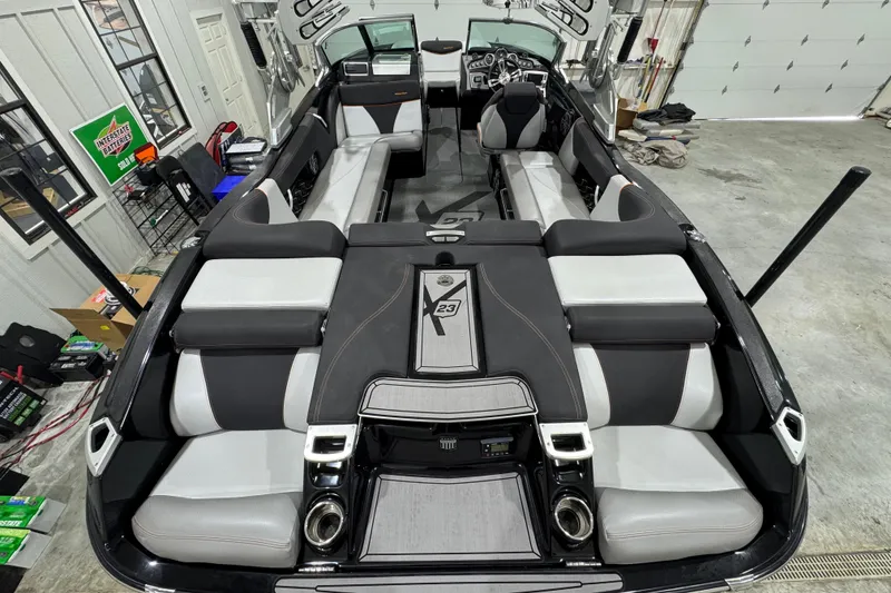 Slide: The Image of 2017 MasterCraft X23 boat interior with sleek seating and modern design in a garage setting. - 9