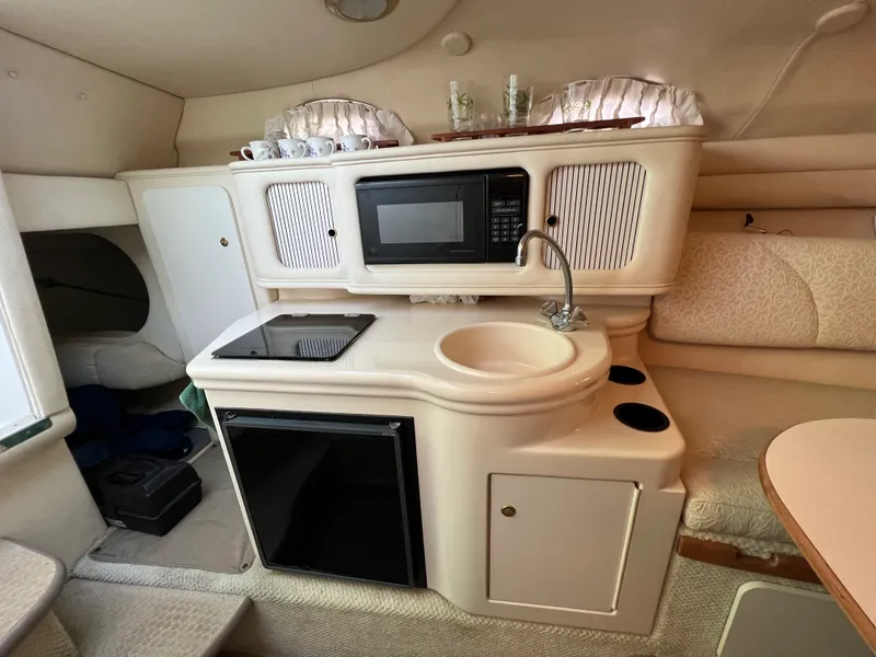 Slide: The Image of 2001 Sea Ray 260 Sundancer cabin interior with kitchenette, microwave, sink, and seating area. - 10