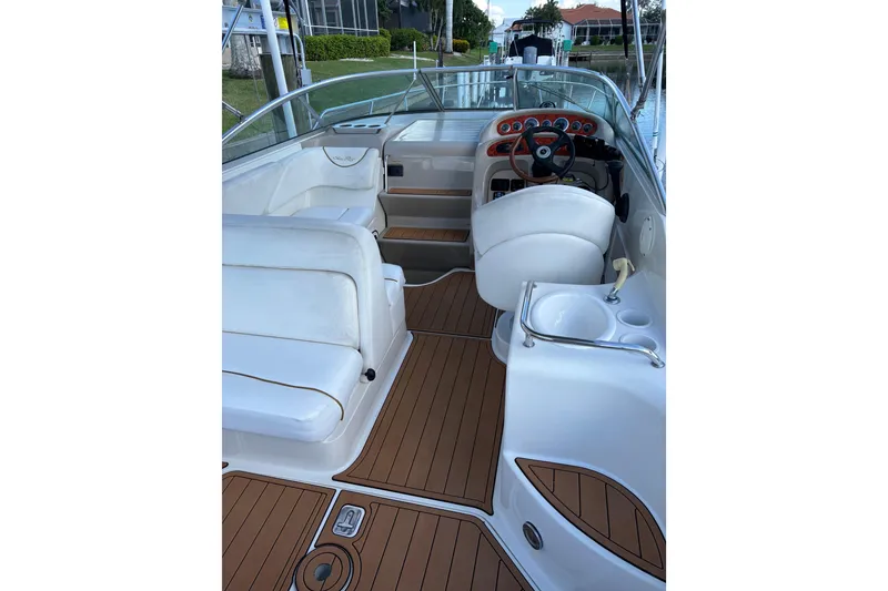 Slide: The Image of 2001 Sea Ray 260 Sundancer boat interior with white seating and wood-style flooring. - 4