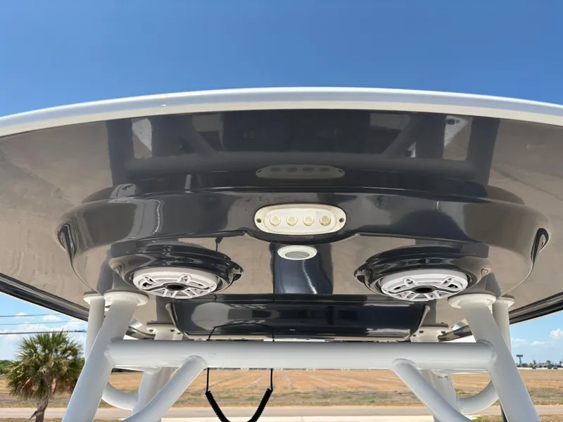 Slide: The Image of 2021 Sportsman Heritage 241 Center Console T-top with speakers and lights, under clear blue sky. - 21