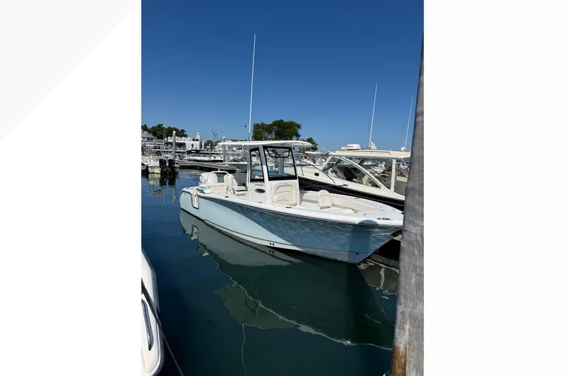 The Image of 2025 Sea Hunt Ultra 255 SE boat docked in a marina under clear blue skies. - 0