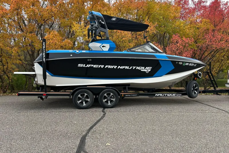 Slide: The Image of 2019 Nautique Super Air Nautique G21 boat on trailer, autumn trees in background. - 2