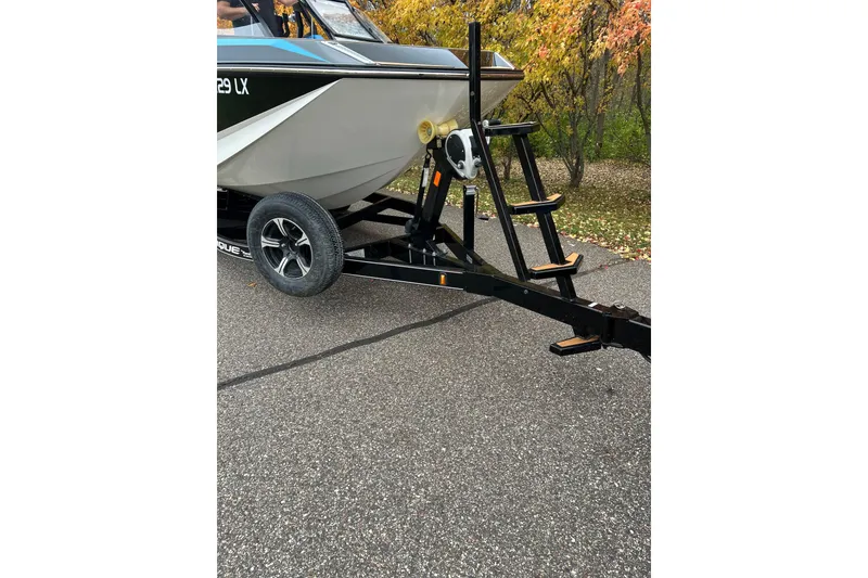 Slide: The Image of 2019 Nautique Super Air Nautique G21 on trailer, parked on asphalt with autumn foliage background. - 5