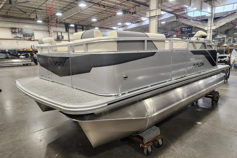 Slide: The Image of 2026 Avalon Venture Cruise Rear Bench pontoon boat in a spacious indoor facility. - 15
