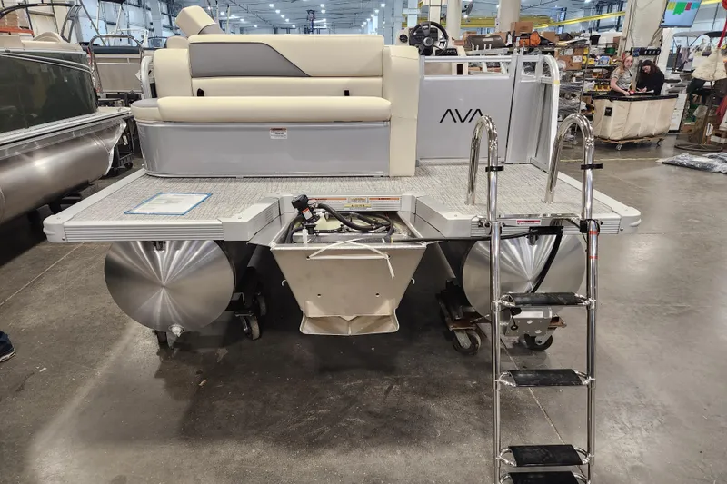 Slide: The Image of 2026 Avalon Venture Cruise Rear Bench pontoon boat in a showroom, featuring a ladder and seating. - 16