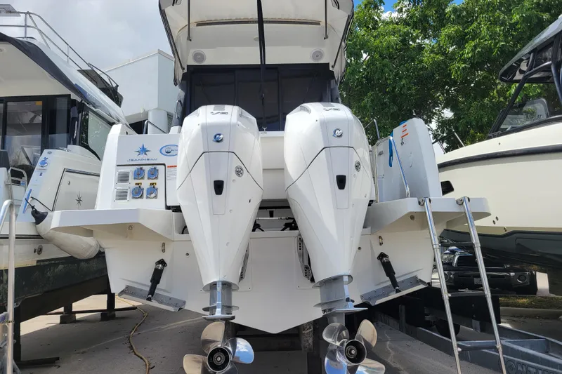 Slide: The Image of 2023 Jeanneau NC 895 boat with dual outboard engines, docked outdoors. - 29