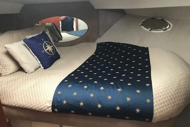 Slide: The Image of 1997 Silverton 352 Motor Yacht bedroom with nautical-themed bedding and porthole window. - 19