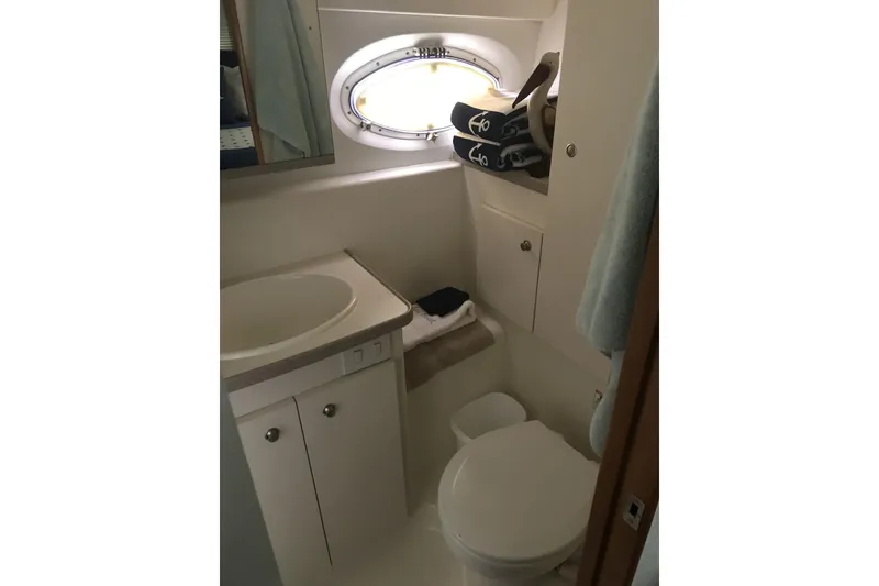 Slide: The Image of Bathroom interior of 1997 Silverton 352 Motor Yacht with sink, toilet, and porthole window. - 26
