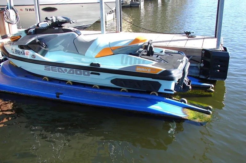 Slide: The Image of 2022 Sea-Doo Wake Pro 230 jet ski docked on a blue platform by the water. - 15