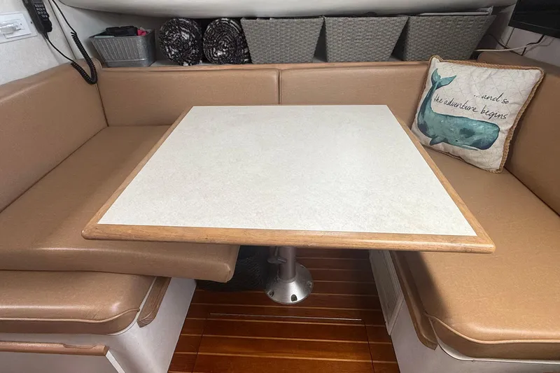 Slide: The Image of 1997 Blackfin Combi 33 interior with beige seating and a table, featuring a decorative pillow. - 12