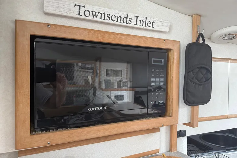 Slide: The Image of Microwave in 1997 Blackfin Combi 33 boat kitchen, with "Townsends Inlet" sign above. - 16