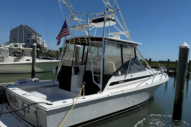Slide: The Image of 1997 Blackfin Combi 33 boat docked, featuring an American flag and clear skies. - 40